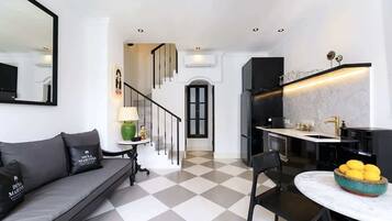 Une cuisine moderne avec un plan de travail en marbre, des meubles noirs et un canapé noir assorti à des coussins du même coloris.