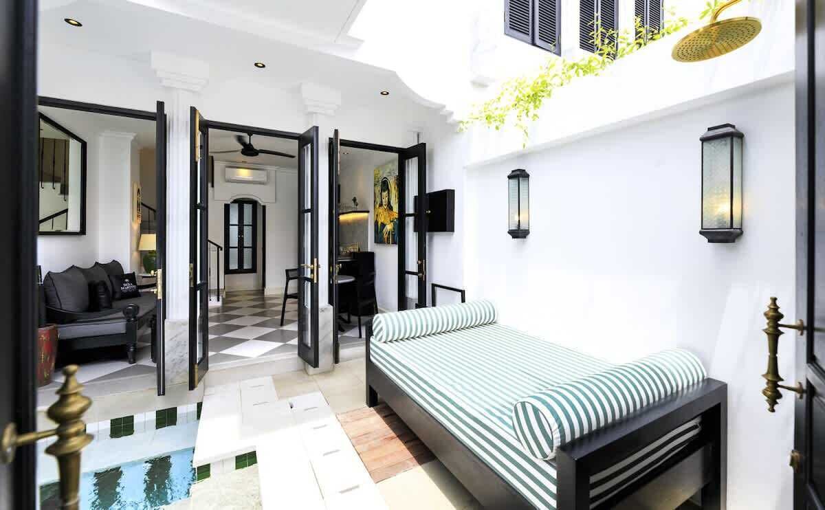 Une chambre d’hôtel avec un lit, un bureau, une chaise et un canapé. Il y a une fenêtre donnant sur l’extérieur.