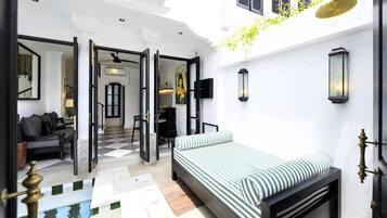 Une chambre d’hôtel avec un lit, un bureau, une chaise et un canapé. Il y a une fenêtre donnant sur l’extérieur.