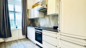A modern kitchen with white cabinets, a stove, and a window with curtains. - Affordable Room in Shared Apt. Close to Stadthalle (Vienna)