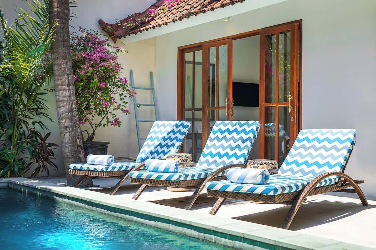 A poolside area with lounge chairs and a palm tree.