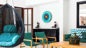 Ein Wohnzimmer mit Hängekorbschaukel, Holzstühlen, einer Couch, einem Couchtisch und einer Wandplatte.