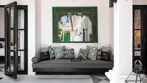 A modern living room with a grey sofa, patterned cushions, and a large mirror above it. - Villa Nago · 2 King Suites · Walk to Potato Head (Kerobokan Kelod)