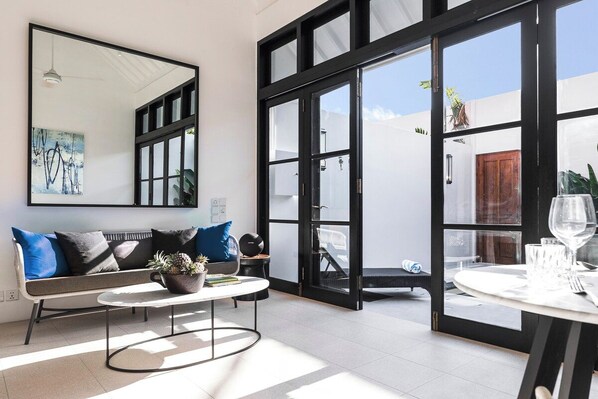 Una sala de estar moderna con un sofá, una mesa de centro y un comedor con una mesa dispuesta para dos personas.