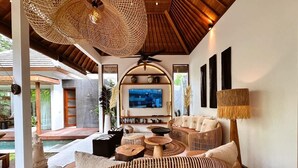 A modern living room with a TV, wicker furniture, and a ceiling fan. - Tropical Cozy 4BR Villa Pacha Seminyak Up to 12pax (Seminyak)