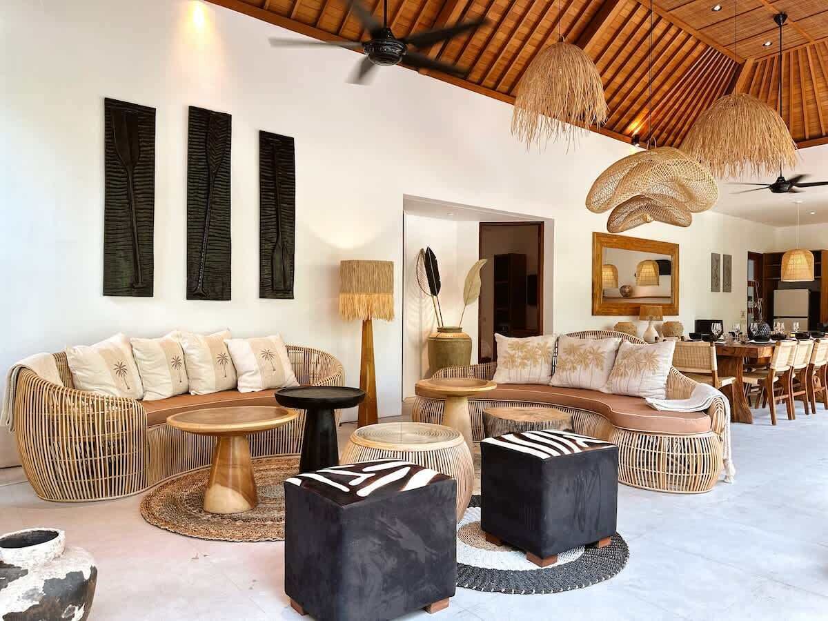 A spacious living area with a high ceiling, woven furniture, and a large dining table.