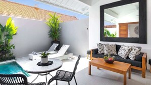 A modern outdoor living space with a pool, lounge chairs, a dining table, and a sofa with patterned cushions. - Cozy 1BR Villa Pandi - Walk to Eat Street Seminyak (Seminyak)