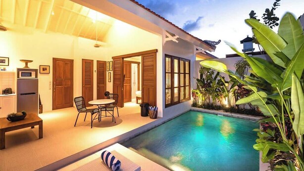 A well-lit outdoor area with a pool, a dining table with chairs, and a lounge area with a sofa. - Cozy 1BR Villa Pandi - Walk to Eat Street Seminyak (Seminyak)