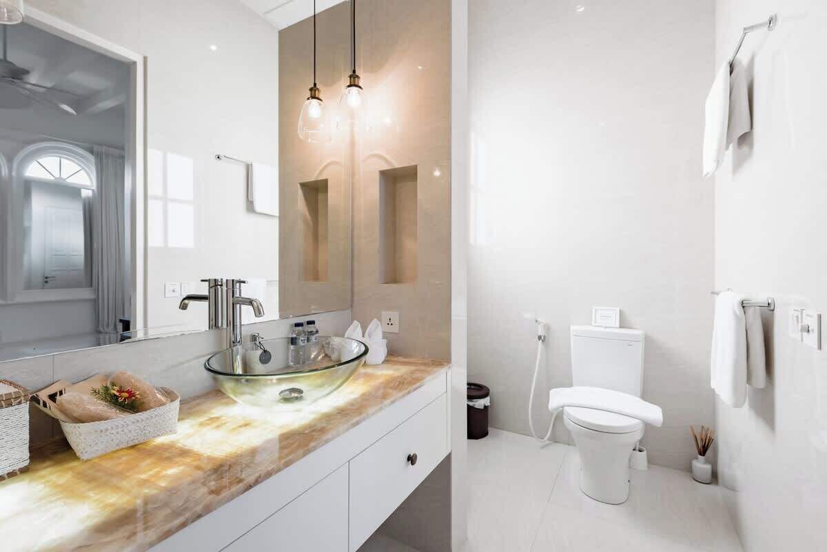 Une salle de bain moderne avec un lavabo en verre, des accessoires blancs et un grand miroir.