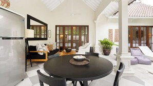 A dining area with a round table, chairs, and a black tablecloth. There is a sofa with cushions and a potted plant in the background. - Exclusive 2BR I Walk to Seminyak Mall & the Beach (Kerobokan Kelod)
