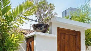 A poolside area with a wooden door, a lantern, and lush greenery. - Exclusive 2BR I Walk to Seminyak Mall & the Beach (Kerobokan Kelod)