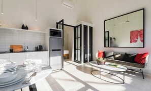 A modern kitchen with white cabinets, a built-in microwave, and a dining area with a round table and chairs.