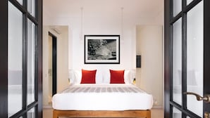 Un dormitorio con una cama, un cuadro enmarcado en la pared y una puerta con paneles de vidrio.