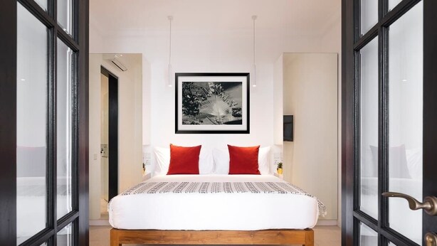 A bedroom with a bed, a framed picture on the wall, and a door with glass panels. - Villa Saffron – Walk to Seminyak's Best Cafe Shop (Kerobokan Kelod)
