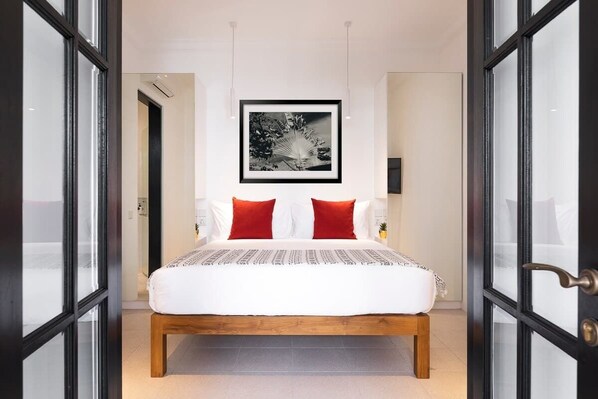 A bedroom with a bed, a framed picture on the wall, and a door with glass panels.