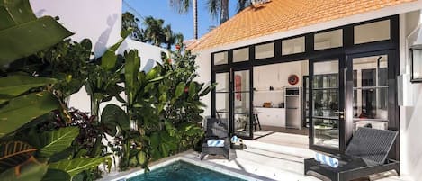 Una casa moderna con piscina, ventanas amplias y plantas tropicales.