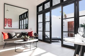 A modern living room with a sofa, coffee table, and dining area.