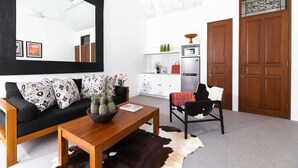 A modern living room with a black-framed mirror, a black sofa with patterned cushions, a wooden coffee table, and a cowhide rug. - Walk around Seminyak Petitenget from 1BR PoolVilla (Kerobokan Kelod)