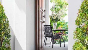 A staircase leading to a covered outdoor area with a table and chairs, surrounded by potted plants. - Walk around Seminyak Petitenget from 1BR PoolVilla (Kerobokan Kelod)