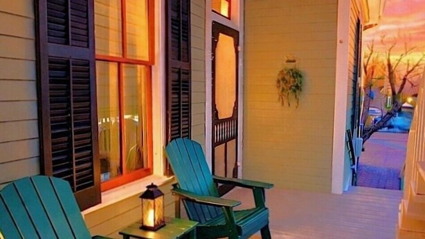 A porch with two green Adirondack chairs and a small table, a lantern, and a decorative mirror on the wall. - 4 Blocks to Beach! • Historic Cottage • 5mins Strand/Port w Driveway Parking (Galveston)