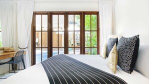 A bedroom with a bed, a desk, and a chair. There is a sliding glass door leading to an outdoor area.