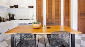 A kitchen with a wooden table, black wire chairs, a stove, and wooden cabinets.