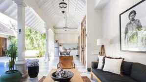 A spacious living area with a checkered floor, a wooden coffee table, a sofa with decorative pillows, and a large framed artwork on the wall.