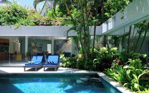 A modern pool area with lounge chairs and lush greenery. - 3BR Villa Ungava | 1 Min to Seminyak Beach (Seminyak)