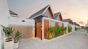 A modern residential area with houses featuring sloped roofs, a gated entrance, and potted plants along the pathway.