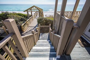 Una escalera de madera que lleva a una zona de playa con un pabellón de madera.