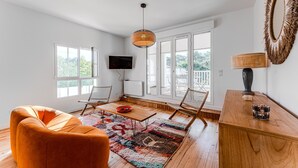 Una sala de estar moderna con sofá, sillones, una mesa de centro, televisor y un ventanal grande.