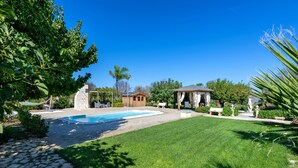 Un jardin avec une piscine, un belvédère et un chemin de pierres.
