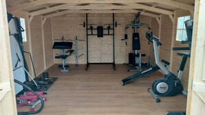 Une salle de sport équipée de divers appareils d’entraînement, notamment un banc de développé couché, un support à squats et un appareil elliptique.