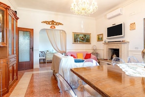 Une chambre d’hôtel équipée d’un lit, d’une table à manger, d’une télévision, d’une cheminée et d’un grand miroir.