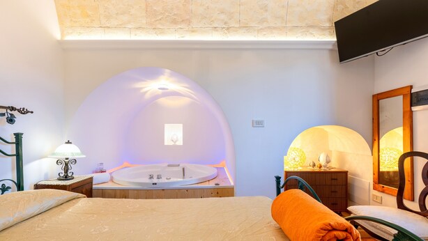 Une chambre à coucher avec un lit, une commode en bois, une baignoire ronde et un miroir.
