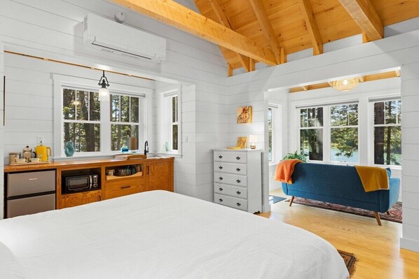 Une chambre à coucher avec un lit, une commode, une coiffeuse et une fenêtre.
