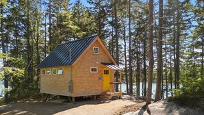 A cabin with a sloped roof, a small porch, and a door. - Lindquist Cottage | Waterfront Studio with King Be (Tenants Harbor)