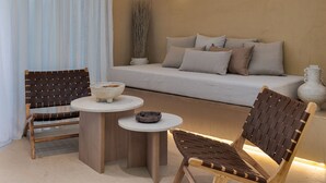 Una zona de estar acogedora con un sofá, dos sillones de mimbre, una mesita redonda y un florero.