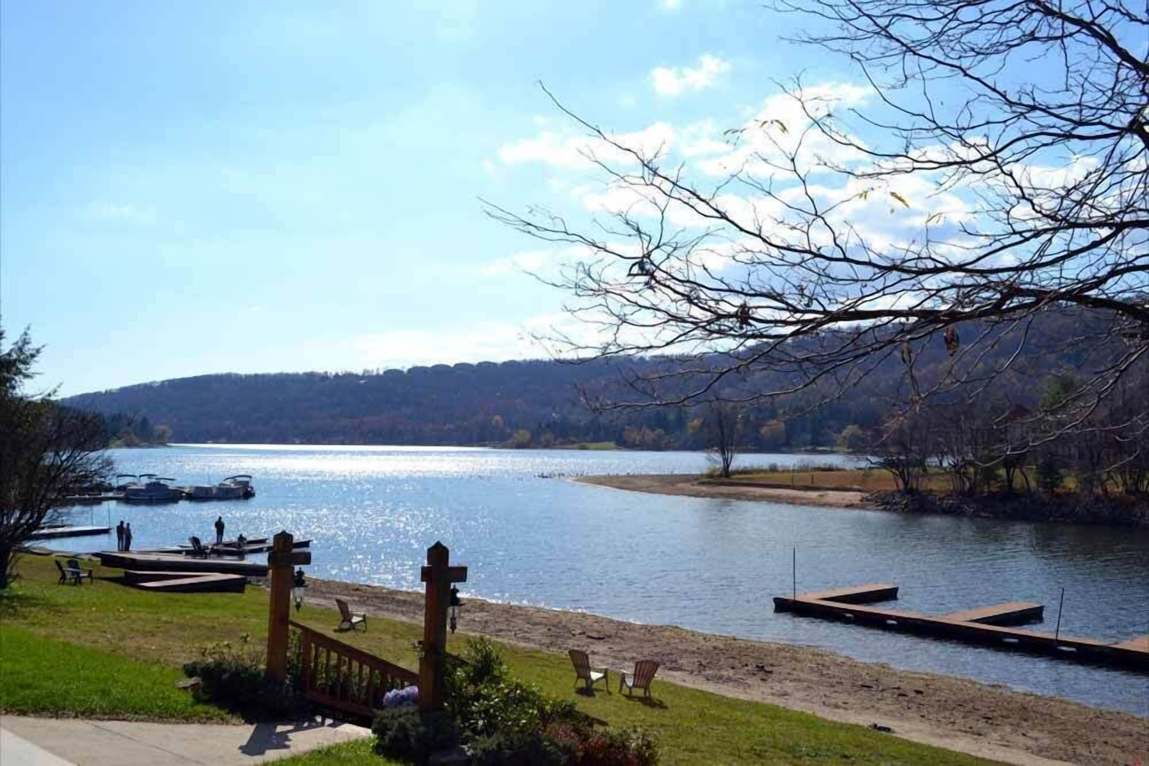 Vista de un lago con un muelle, sillas y una valla de madera.