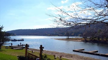 Vista de un lago con un muelle, sillas y una valla de madera.