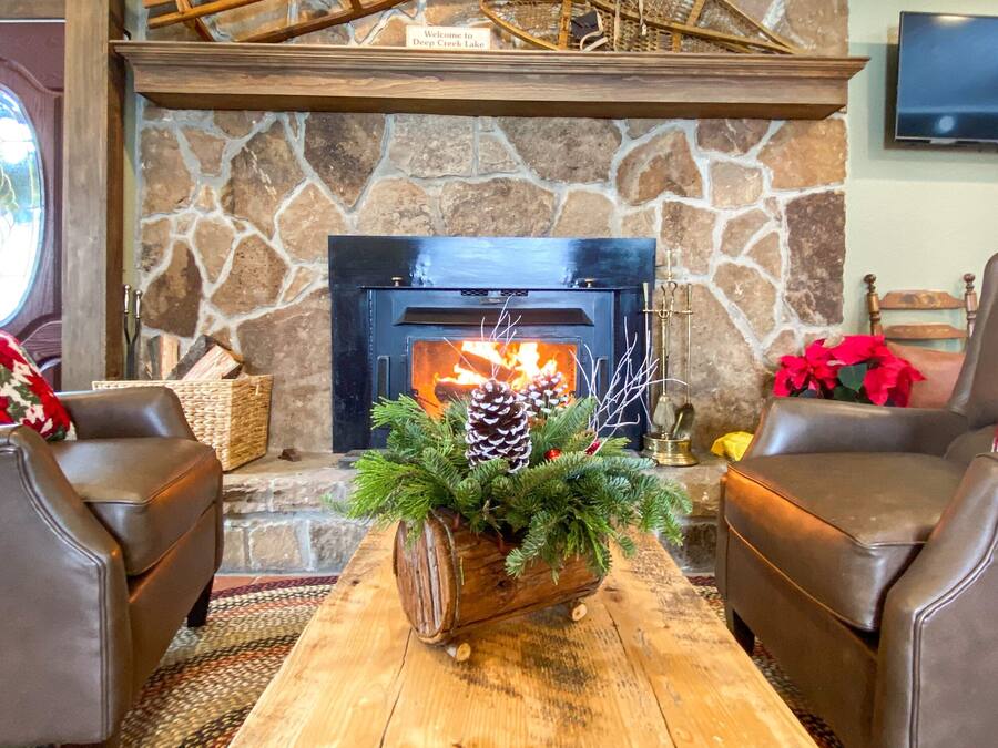 A cozy living room with a stone fireplace, leather chairs, and a decorative centerpiece on a wooden coffee table.