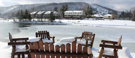 A wooden bench and chairs covered in snow, a snow-covered landscape, and buildings in the background.