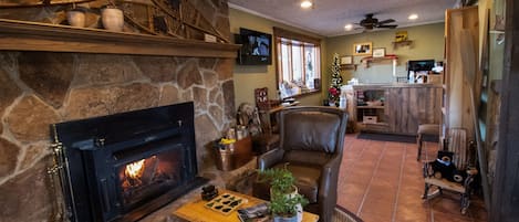 A cozy living room with a stone fireplace, leather armchair, and a wooden coffee table.