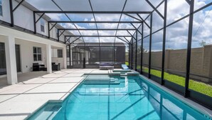 A swimming pool with a glass enclosure, a patio area with outdoor furniture, and a view of a residential building. - Stunning Mansion 15 ensuites (Kissimmee)