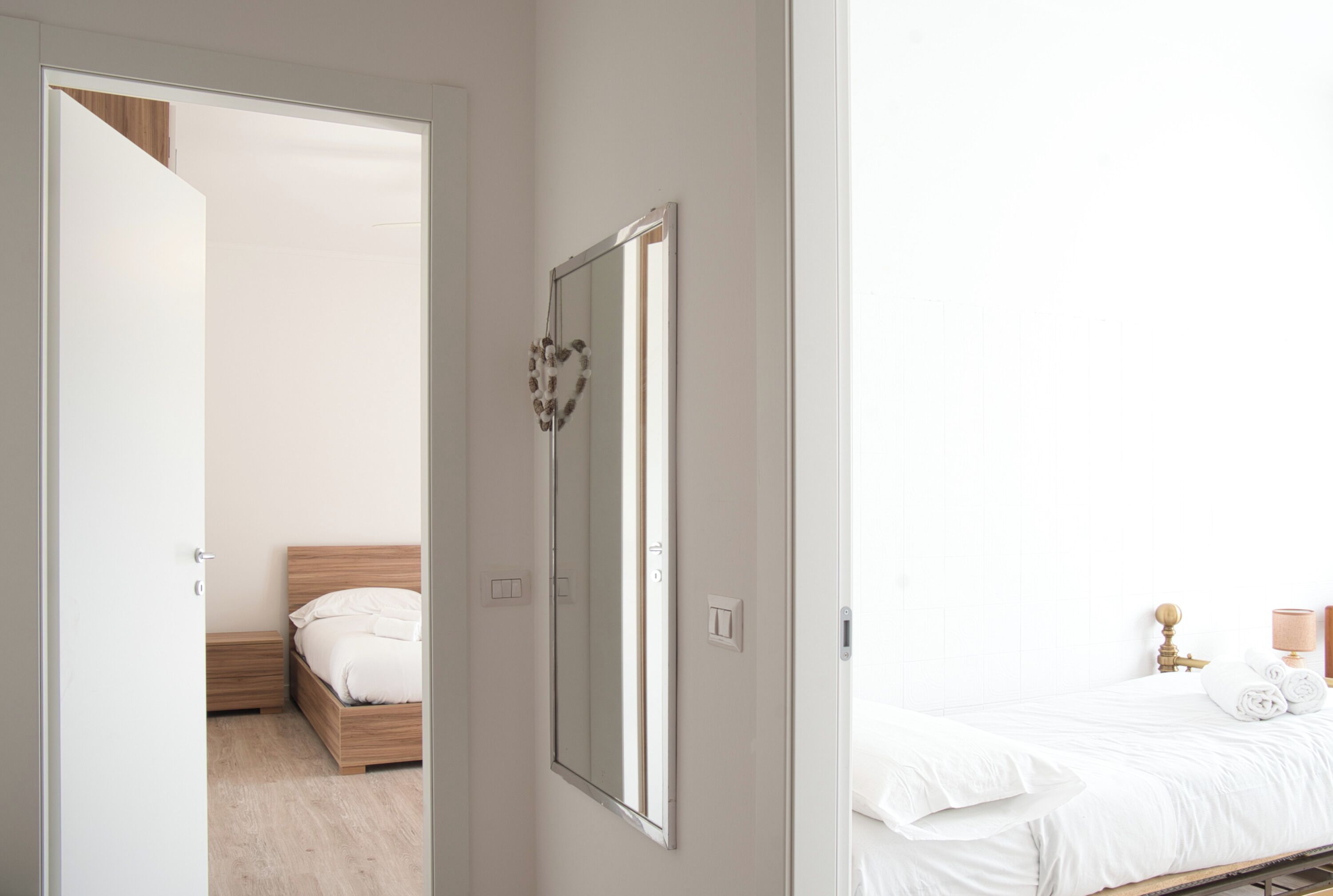 Un dormitorio con una cama de madera, una mesita de noche, un espejo y una mesita auxiliar.