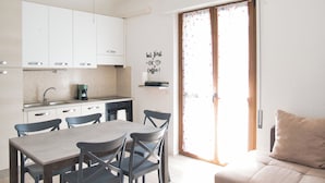 Una cocina moderna con armarios blancos, una mesa de comedor con sillas y una cafetera.
