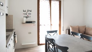 Una cocina moderna con comedor, un letrero de café en la pared y una puerta corrediza de vidrio.