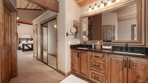 A bathroom with wooden cabinets, a large mirror, and a sink. - Mountain Home on 10-Acres (Fraser)