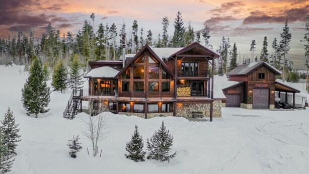 A large log cabin with multiple decks and a stone foundation, surrounded by snow and trees. - Mountain Home on 10-Acres (Fraser)