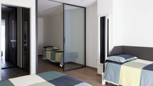 A modern bedroom with a large bed, a smaller bed, and a glass partition.